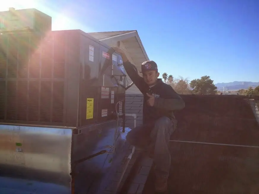 HVAC technician performing Air Duct Cleaning on a rooftop unit in Opelika